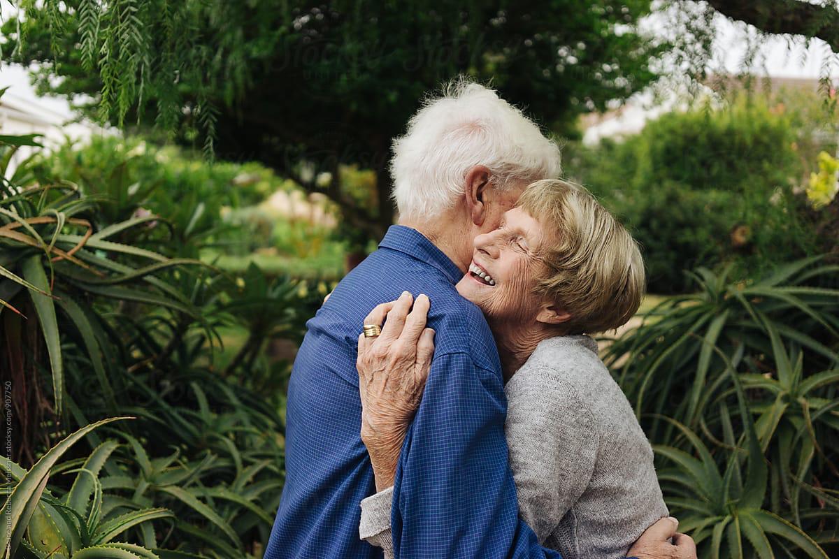 Older man and woman embracing in garden